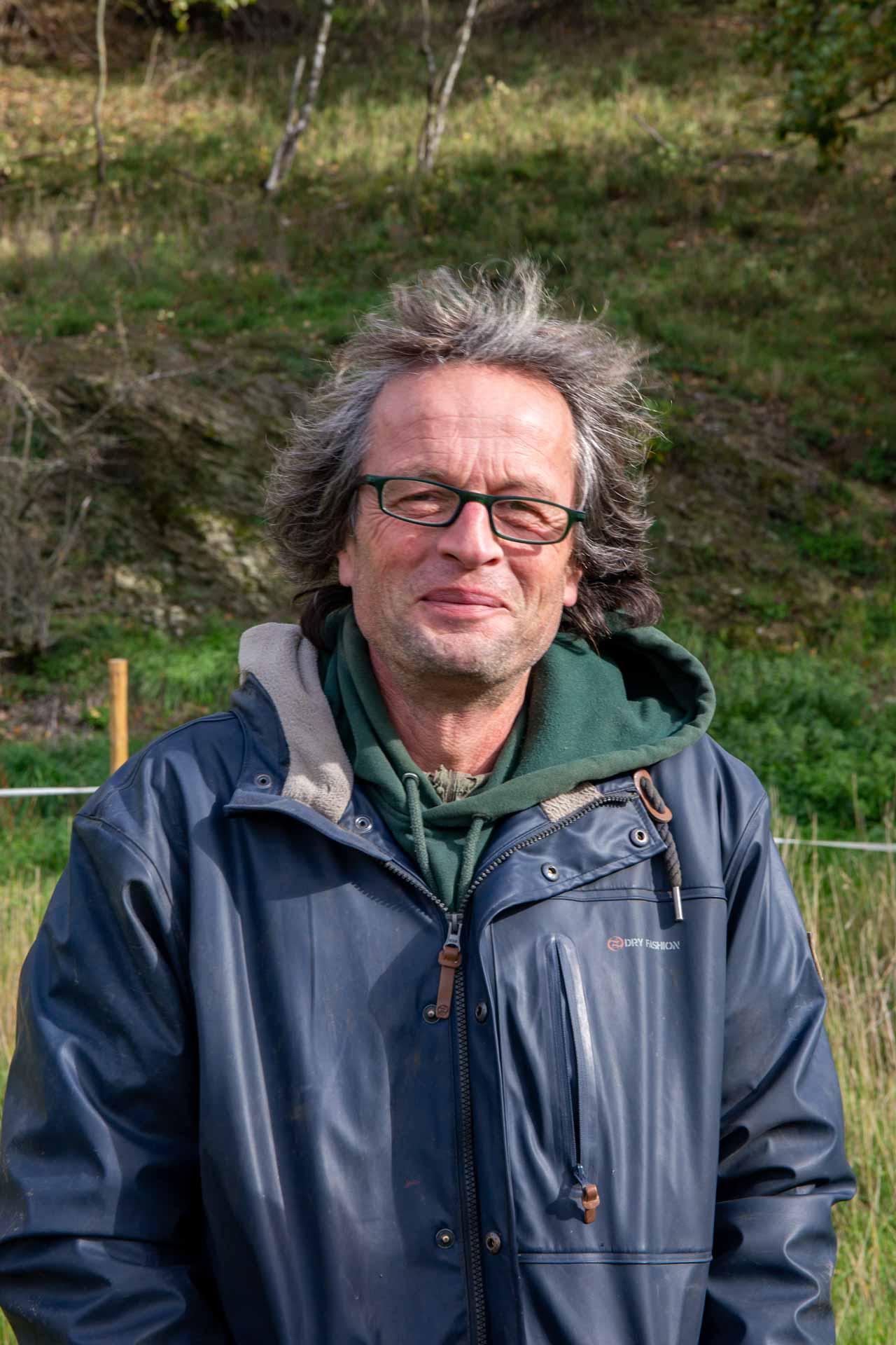 Antonia Brasjno vom Kapellenhof hält ein kleines Lämmchen auf dem Arm und schaut glücklich in die Kamera, während die Mutter des Lämmlings im Hintergrund steht. Der regionale Erzeuger Kapellenhof in Hammersbach ist ein Naturland-zertifizierter Bio-Hof mit artgerechter Schafhaltung.