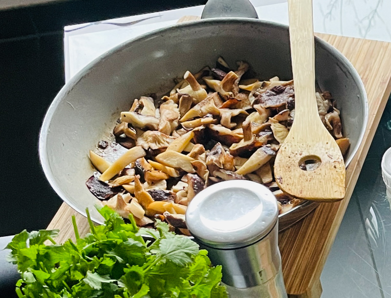 Gedünsstete Pilze in einer Pfanne als Zutat für eine asiatische Suppe.